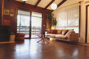 Una sala de estar con un sofá, una mesa de centro de vidrio, una chimenea y un ventanal corredizo que da a un espacio exterior.