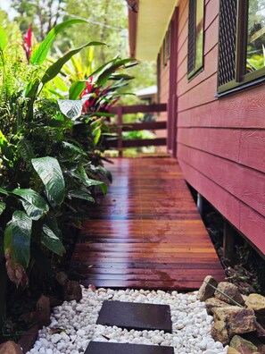 A wooden pathway leading to a building with a red exterior and a covered porch area.