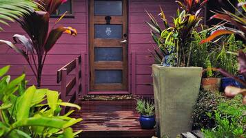 A wooden door with a hand symbol, a red roof, and a gravel pathway leading to a wooden deck.