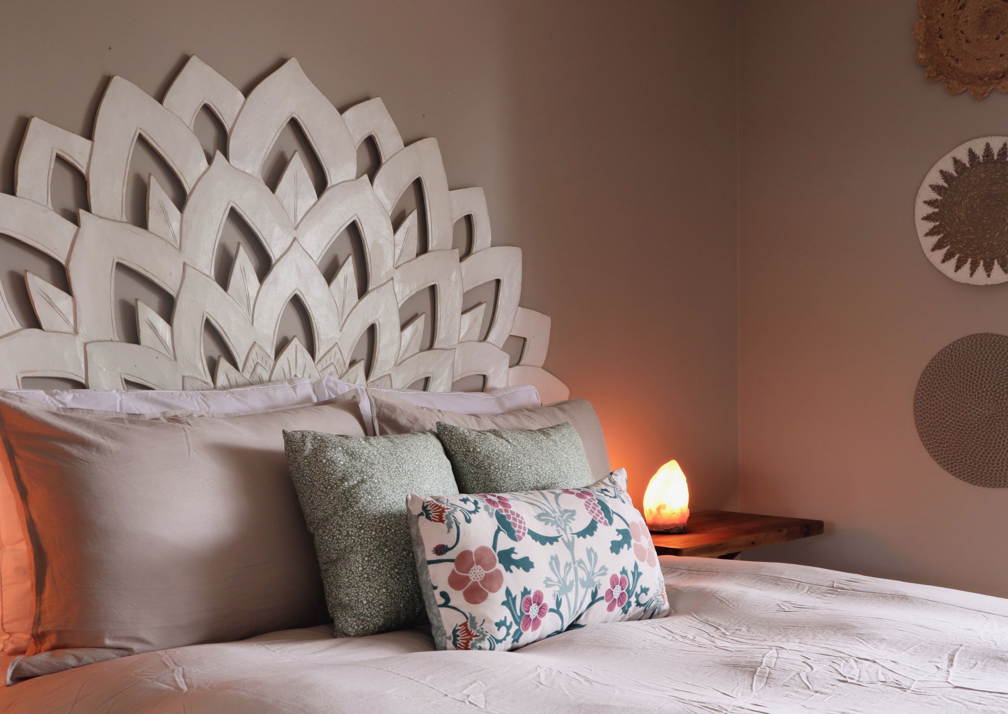 A bed with a decorative headboard, multiple pillows, and a bedside lamp.