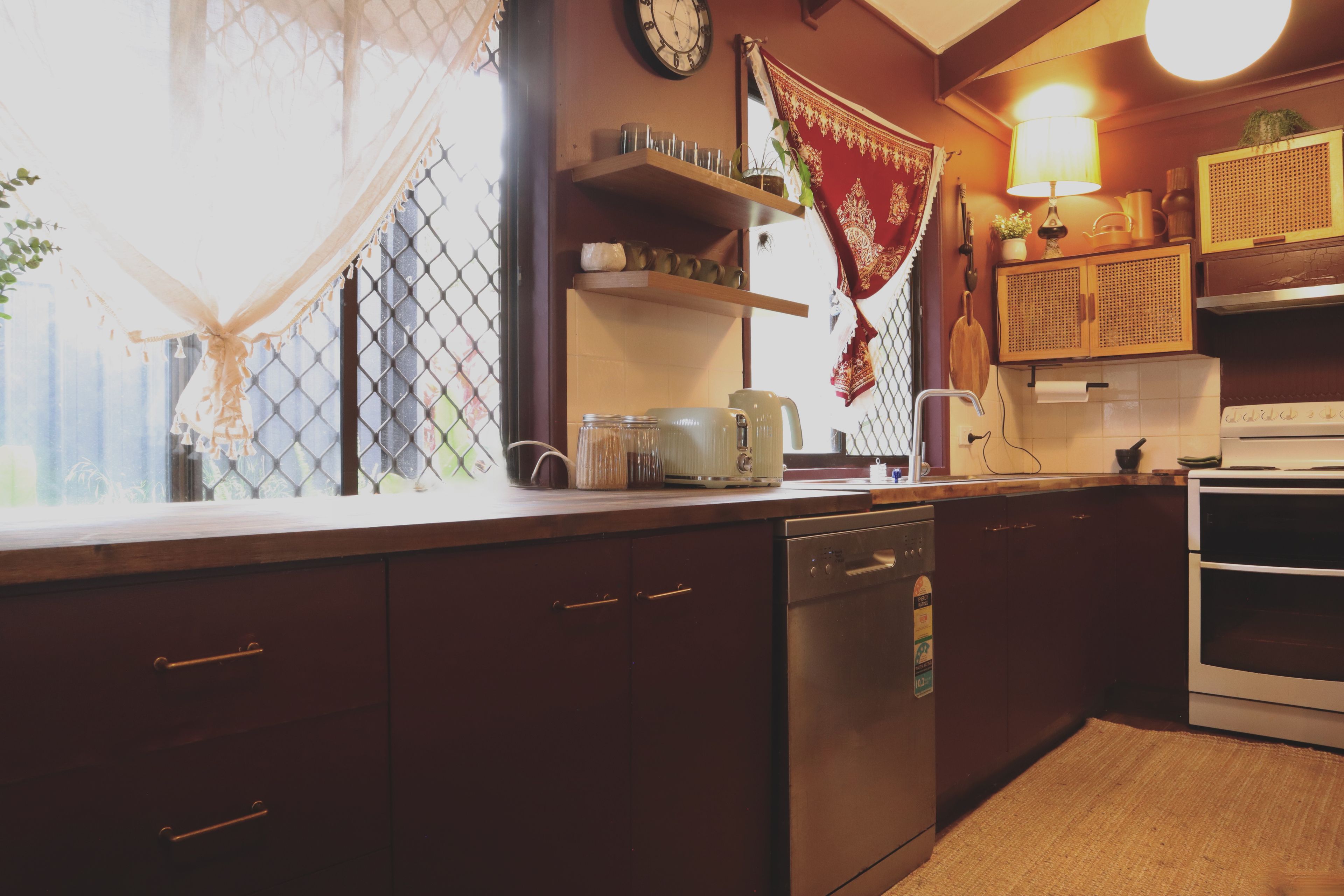 A kitchen with wooden cabinets, a dishwasher, a stove, and various kitchen items on the counter.