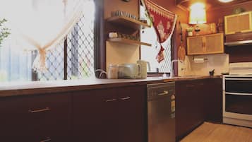 A kitchen with wooden cabinets, a dishwasher, a stove, and various kitchen items on the counter.