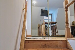 Eine Holztreppe mit einem Spiegel, der einen Essbereich mit Tisch und Stühlen widerspiegelt.