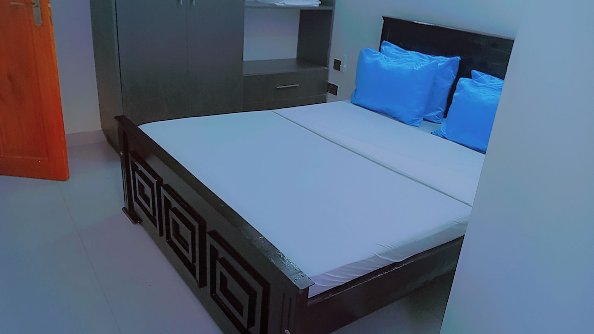 A bedroom with a bed, a wardrobe, and a door.