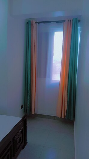 Ein Zimmer mit Fenster, Tür und Vorhang.