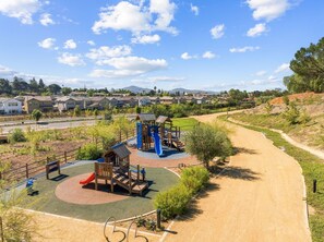 A playground with a slide and climbing structures, surrounded by a dirt path and greenery. - Escondido Modern Escape I Fully Remodeled I Central Location (Escondido)