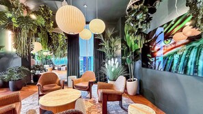 A modern lounge area with wicker furniture, hanging plants, and pendant lighting. - Elegant Miami Escape | Sleeps 4 | Pool & Views (Miami)