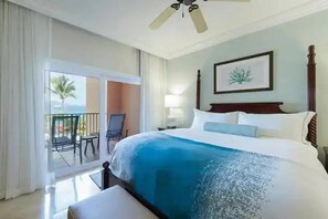 Ein Hotelzimmer mit Bett, Balkon mit Stühlen, Deckenventilator und einem gerahmten Bild an der Wand.