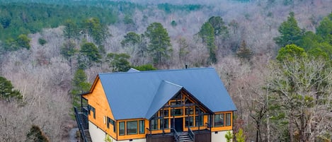 A cabin with a sloped roof, large windows, and a staircase leading to the entrance.
