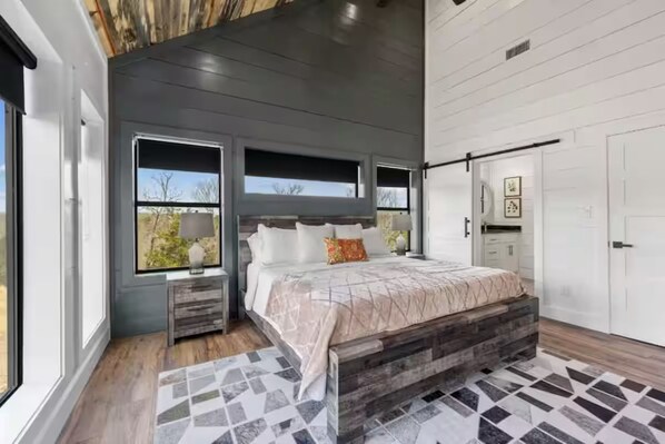 A bedroom with a large bed, a nightstand, a dresser, and a window with a view. - Panoramic views, Creek, Total Privacy, 1 of a Kind (Broken Bow)