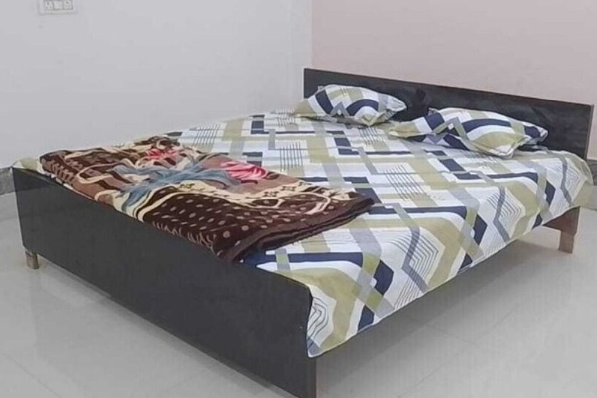 A bed with a patterned bedspread and pillows, a dark headboard, and a tiled floor.