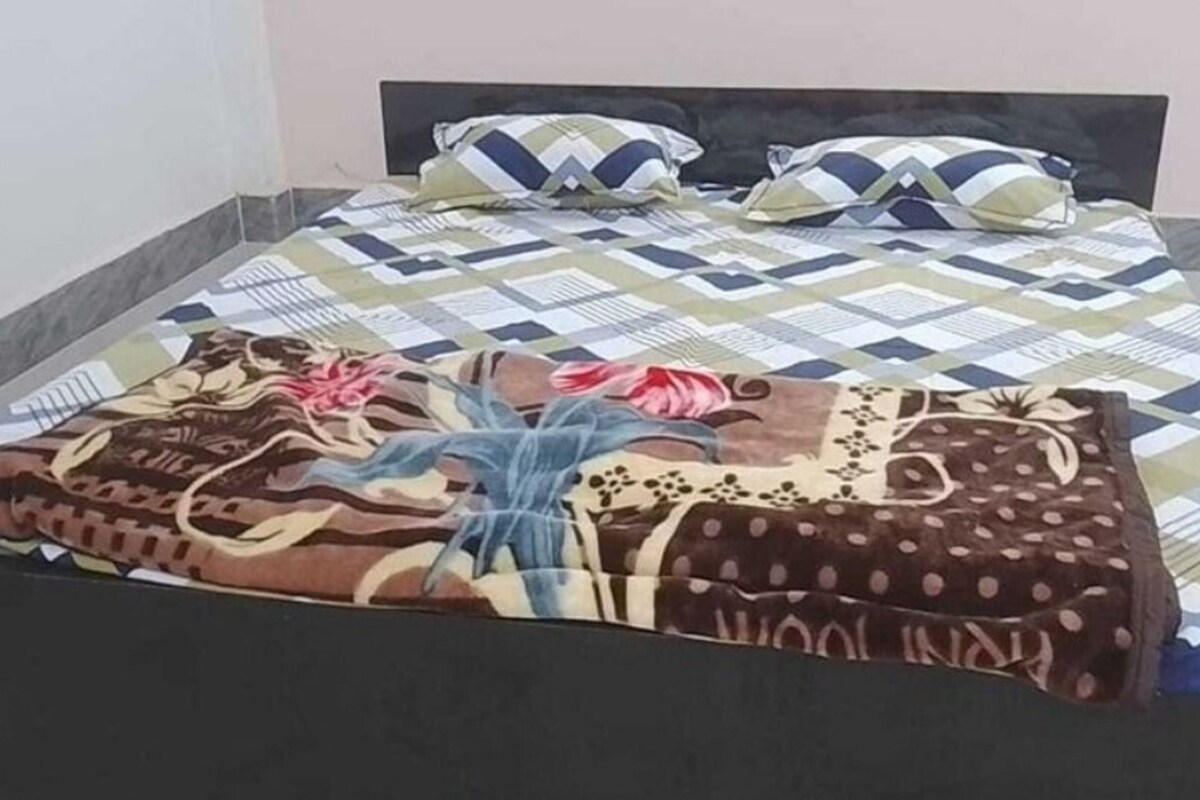Een bed met een bedovertrek met patroon, kussens en een dekbed.