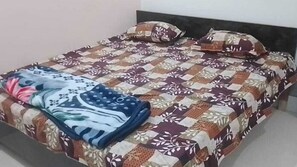 Een bed met een beddegoed met patroon en kussens, een deken en een hoofdbord.