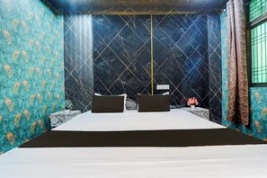 Een kamer met een bed, twee kussens, een nachtkastje met een plant en een raam met gordijnen.