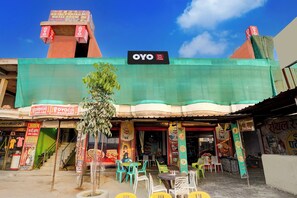 A hotel with a signboard for OYO rooms, outdoor seating, and a staircase leading to the entrance. - Hotel O Royal Prayag (Soraon)