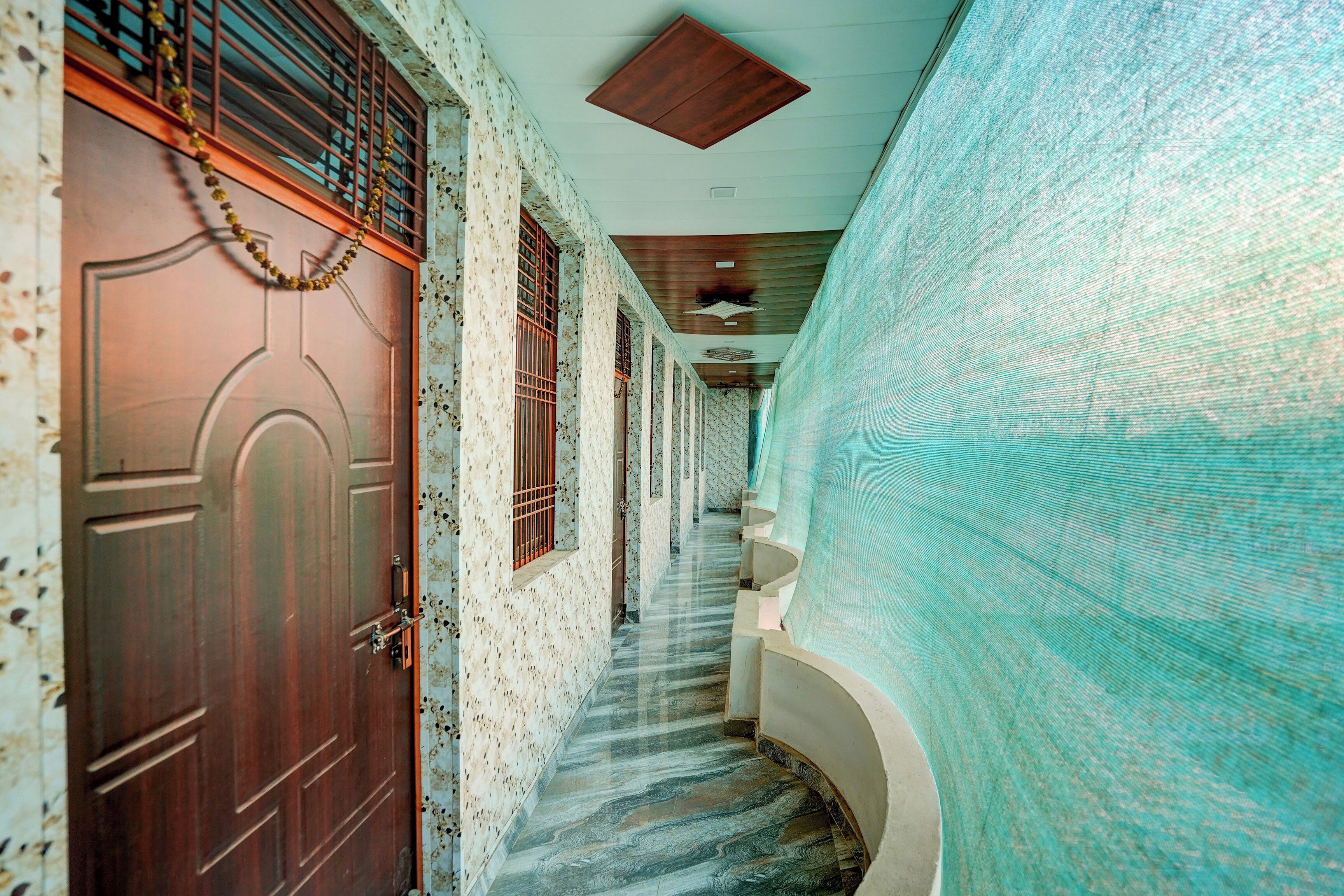 Un pasillo con puerta de madera, paredes con diseño y suelo de baldosas.