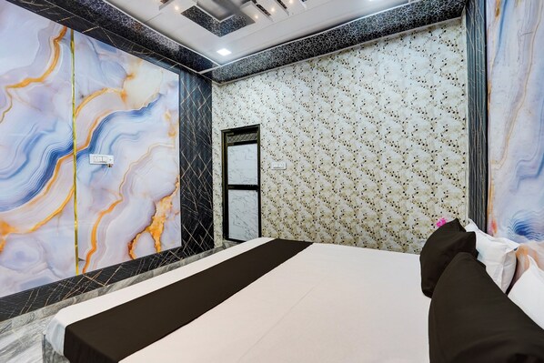 A hotel room with a bed, a mirror, and a patterned wall. - Hotel O Royal Prayag (Soraon)