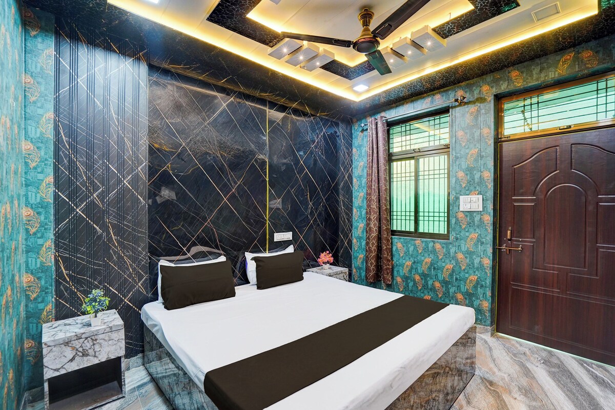 Een hotelkamer met een bed, een raam met gordijnen, een deur en een plafondventilator.