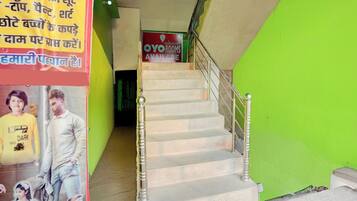 A staircase with a green wall on one side and a sign for OYO rooms in the background.