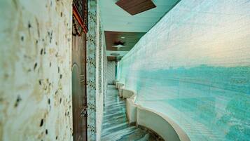 A corridor with a patterned floor, a staircase, and a wall with a textured surface.