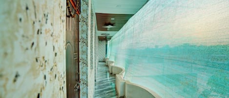 A corridor with a patterned floor, a staircase, and a wall with a textured surface.