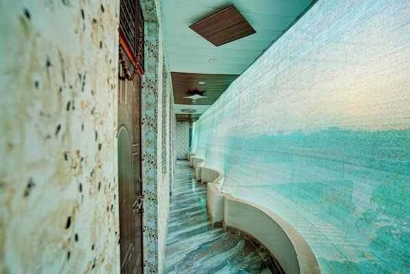 A corridor with a patterned floor, a staircase, and a wall with a textured surface. - Hotel O Royal Prayag (Soraon)