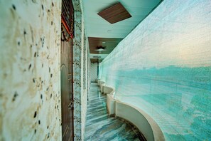 A corridor with a patterned floor, a staircase, and a wall with a textured surface. - Hotel O Royal Prayag (Soraon)
