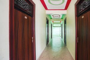 Un pasillo con puertas de madera, numeradas 103 y 102, que conduce a una habitación con techo verde y blanco.