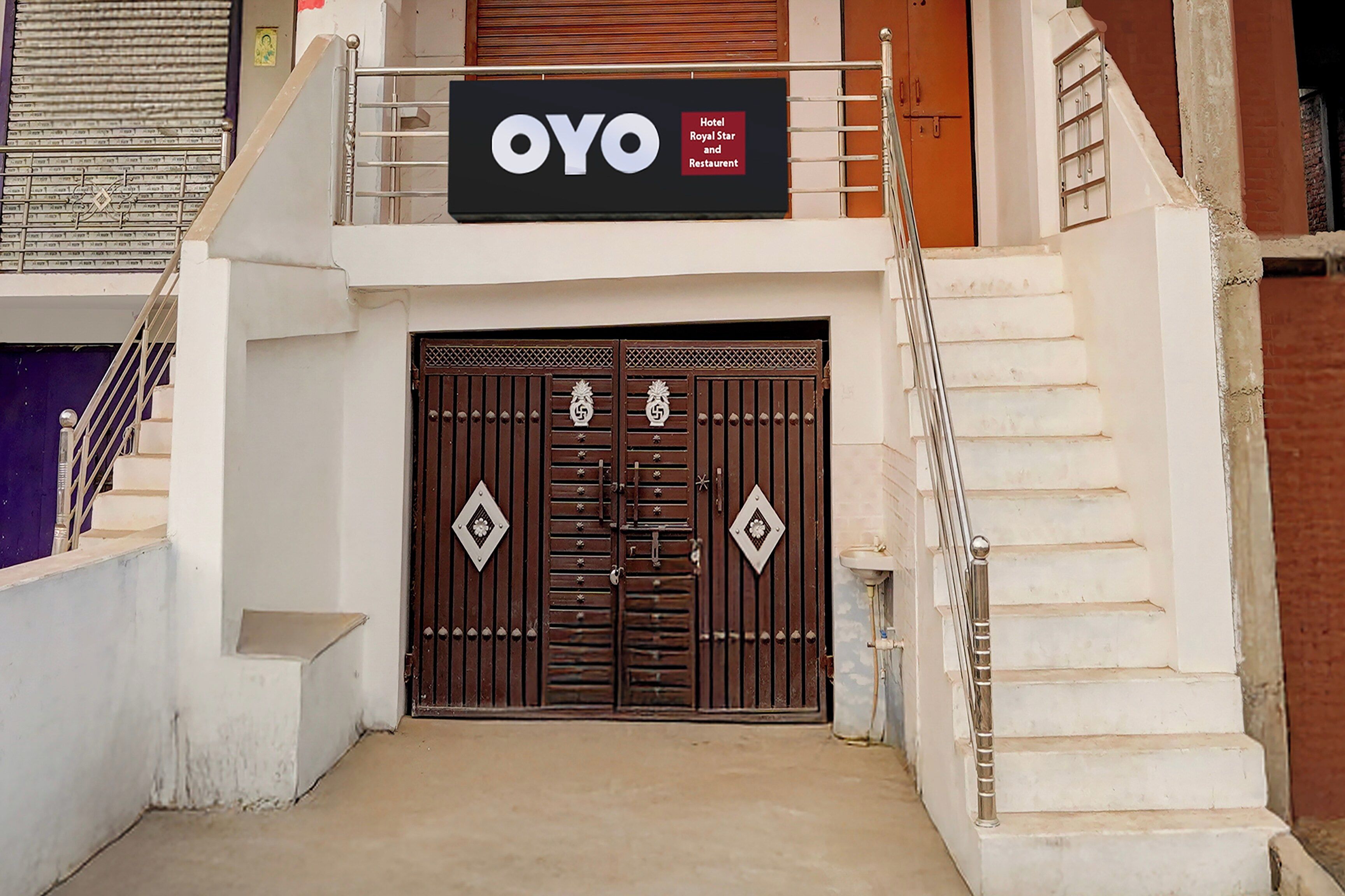 Entrada de un hotel con un gran cartel que dice 'OYO Hotel Royal Star and Restaurant'.