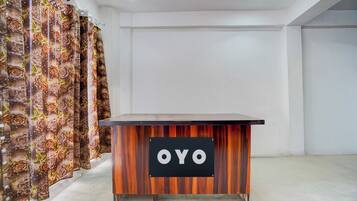 Una recepción con un letrero que dice 'OYO' en un interior moderno con paredes lisas y una cortina estampada.