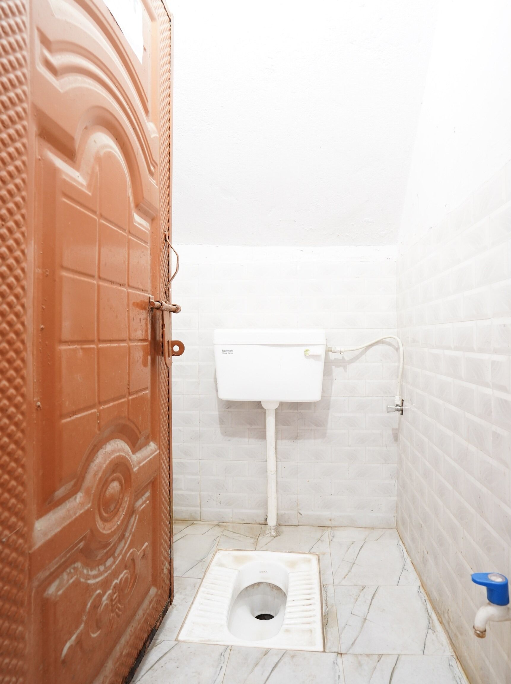 A small, compact bathroom with a toilet, a white sink, and a door with a decorative pattern.