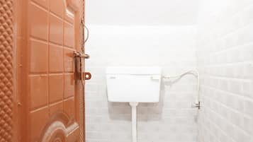 A small, compact bathroom with a toilet, a white sink, and a door with a decorative pattern.