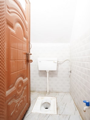 Un baño pequeño y funcional con un inodoro, un lavabo blanco y una puerta con un diseño decorativo.