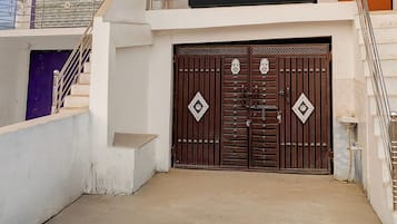 Una entrada protegida por una reja con una escalera que sube a un balcón.