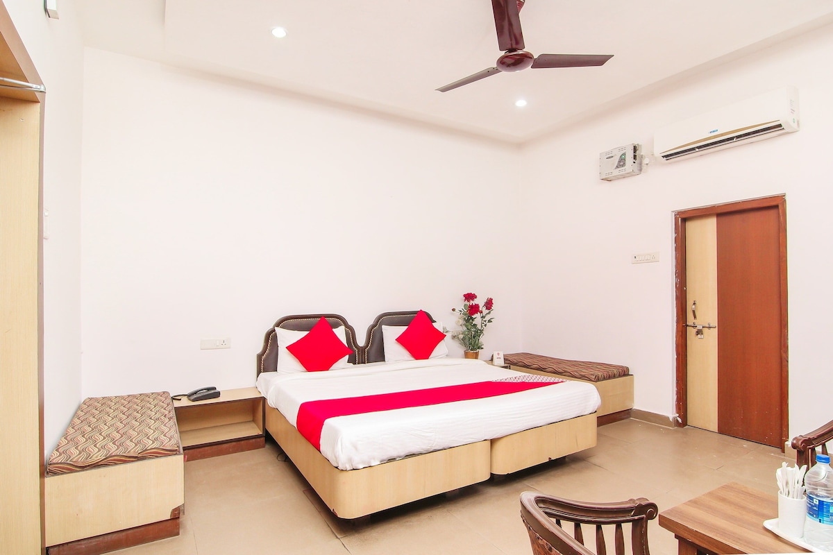 Habitación de hotel con cama, mesitas de noche, escritorio, silla, ventilador de techo y aire acondicionado.