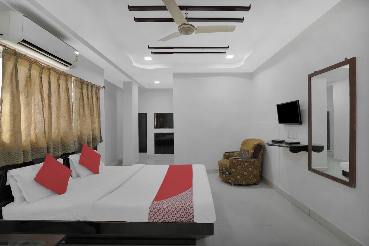 A hotel room with a bed, a chair, a television, and a ceiling fan.