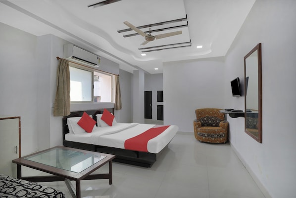 A hotel room with a bed, a glass-top table, a chair, and a television mounted on the wall. - Hotel O Rudra Palace (Ahmedabad)