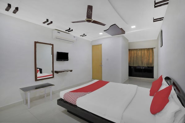 Une chambre à coucher comprenant un lit, un téléviseur, un banc, un climatiseur et un ventilateur de plafond.