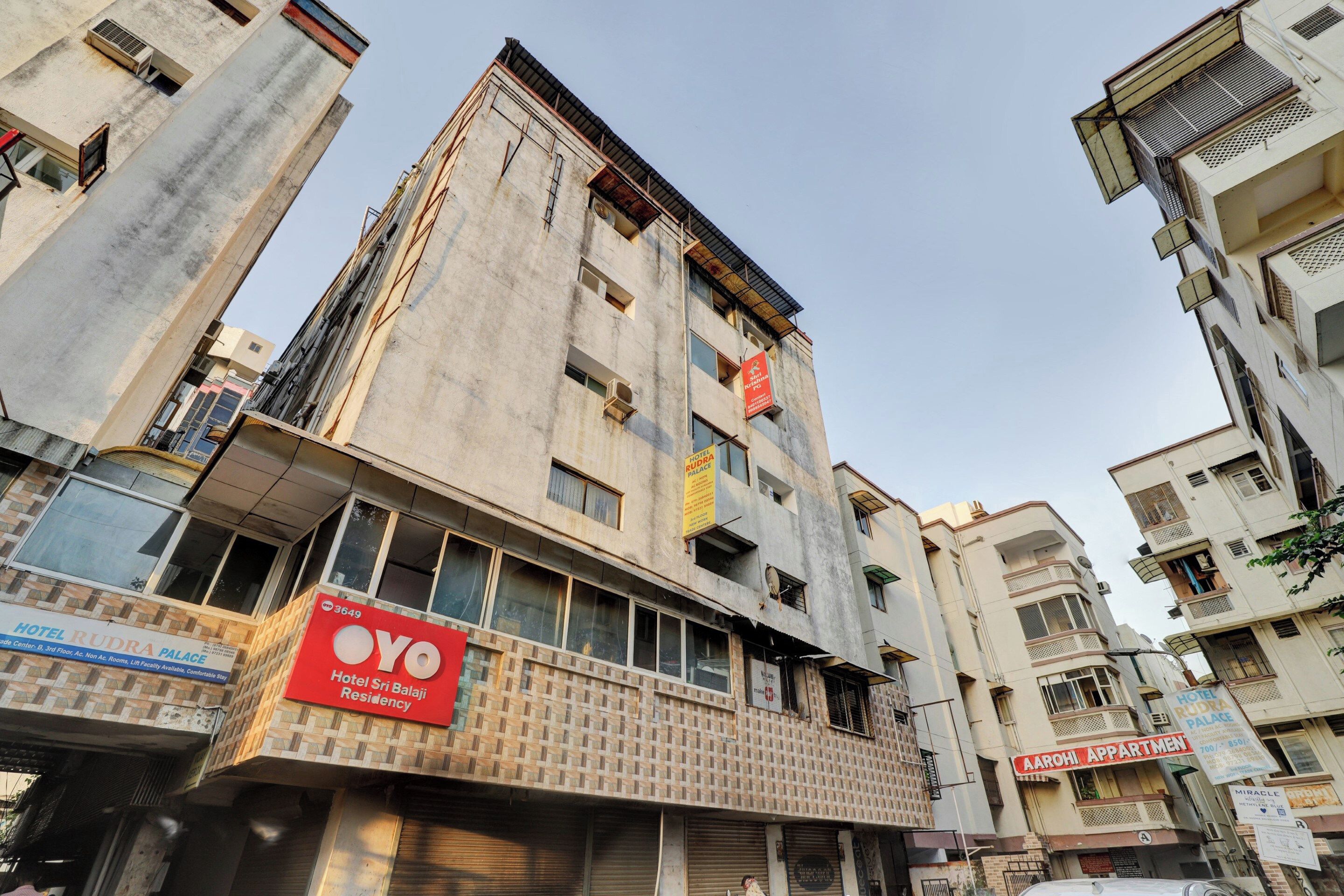 Un edificio de varios pisos con un llamativo letrero rojo que indica Hotel Rudra Palace, mostrando que cuenta con ascensor.