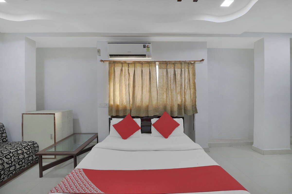 A hotel room with a bed, a nightstand, a chair, a wardrobe, and a window with curtains.