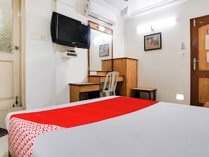 A hotel room with a bed, a desk, a chair, a television, and a wardrobe. - Hotel O Raj Palace (Ahmedabad)
