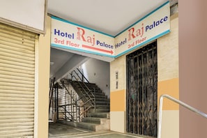 Entrada de un hotel con un letrero que indica el tercer piso y el nombre 'Hotel Raj Palace'.