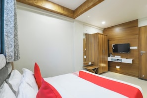 A hotel room with a bed, a TV mounted on the wall, a wardrobe, and a small table with a coffee maker. - Hotel O Madhav Villa (Ahmedabad)