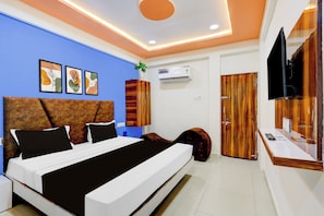 A modern bedroom with a bed, a TV, and a wardrobe. - Hotel O by OYO Shaligram (Ahmedabad)