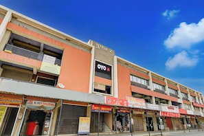 A multi-story building with various businesses including an electronics store, a hotel, and a trading company. - Hotel O by OYO Shaligram (Ahmedabad)
