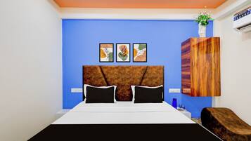 A modern bedroom with a blue accent wall, a wooden headboard, and three framed artworks above the bed.