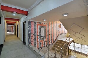 Un couloir d'hôtel avec un escalier menant à un palier situé au troisième étage.