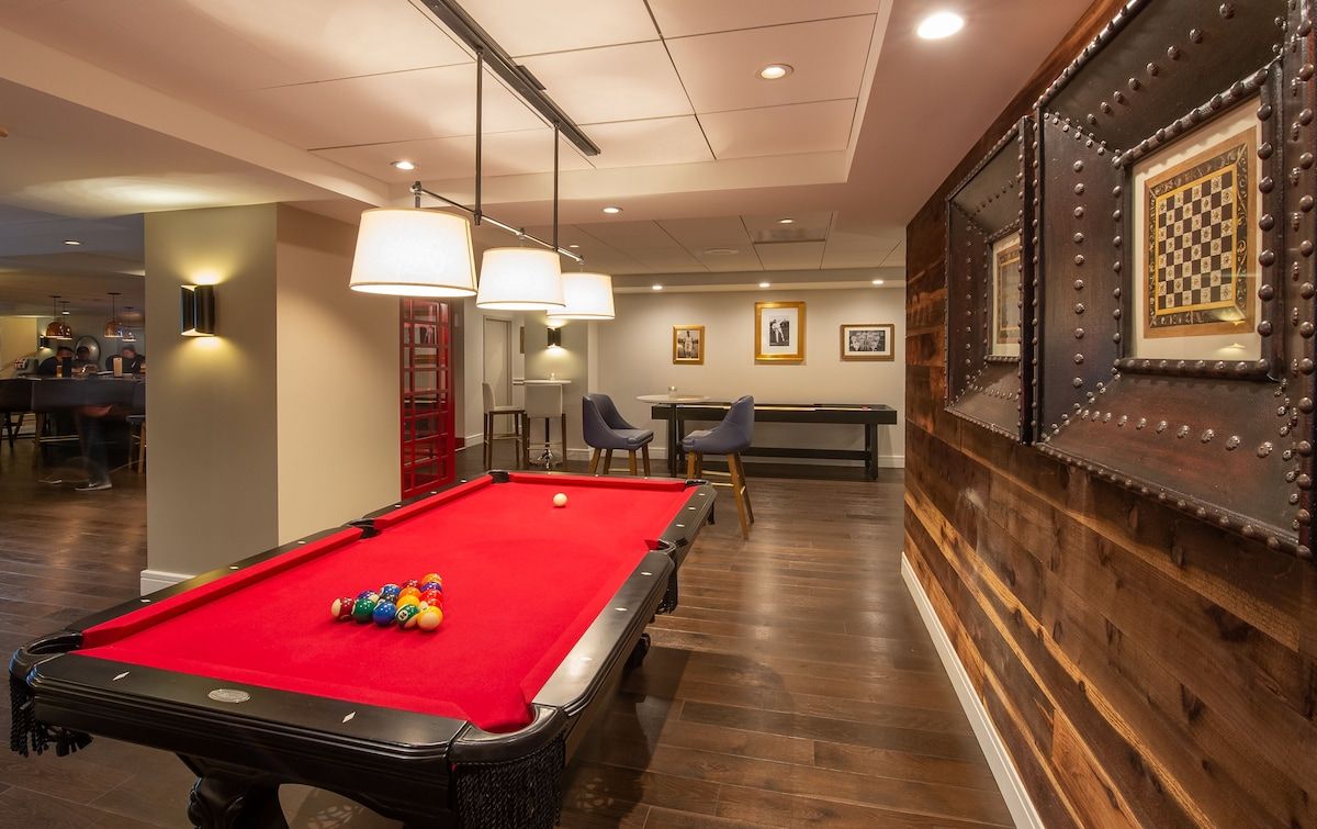 A pool table with balls, a billiard table, and a bar area with chairs.