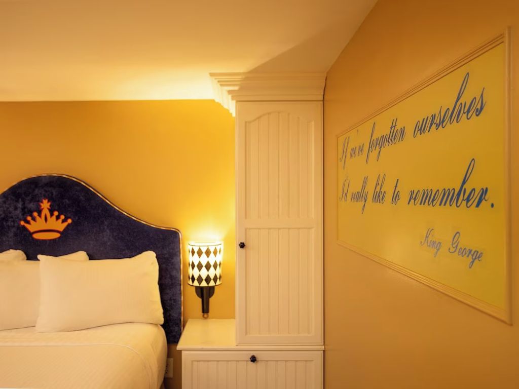 Ein Schlafzimmer mit einem Bett, einem Nachttisch mit Lampe und einer Wand mit einem Zitat.