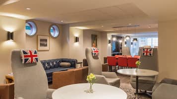 A hotel lobby with seating, tables, and a view of the dining area.